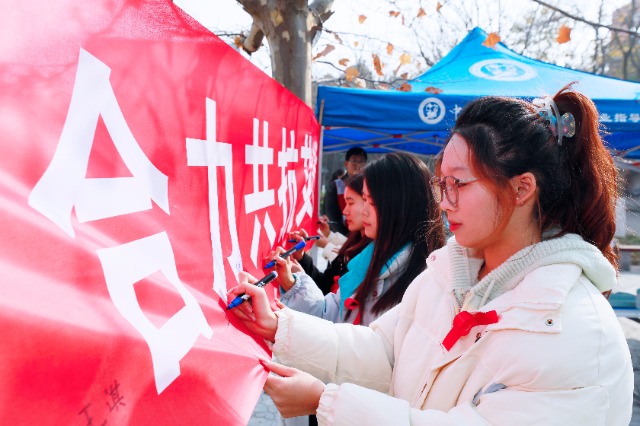 20231127中國石油大學(xué)（華東）青年學(xué)子在合力共抗艾滋的條幅上簽字，表達(dá)抗擊艾滋病的決心和信心  .jpg