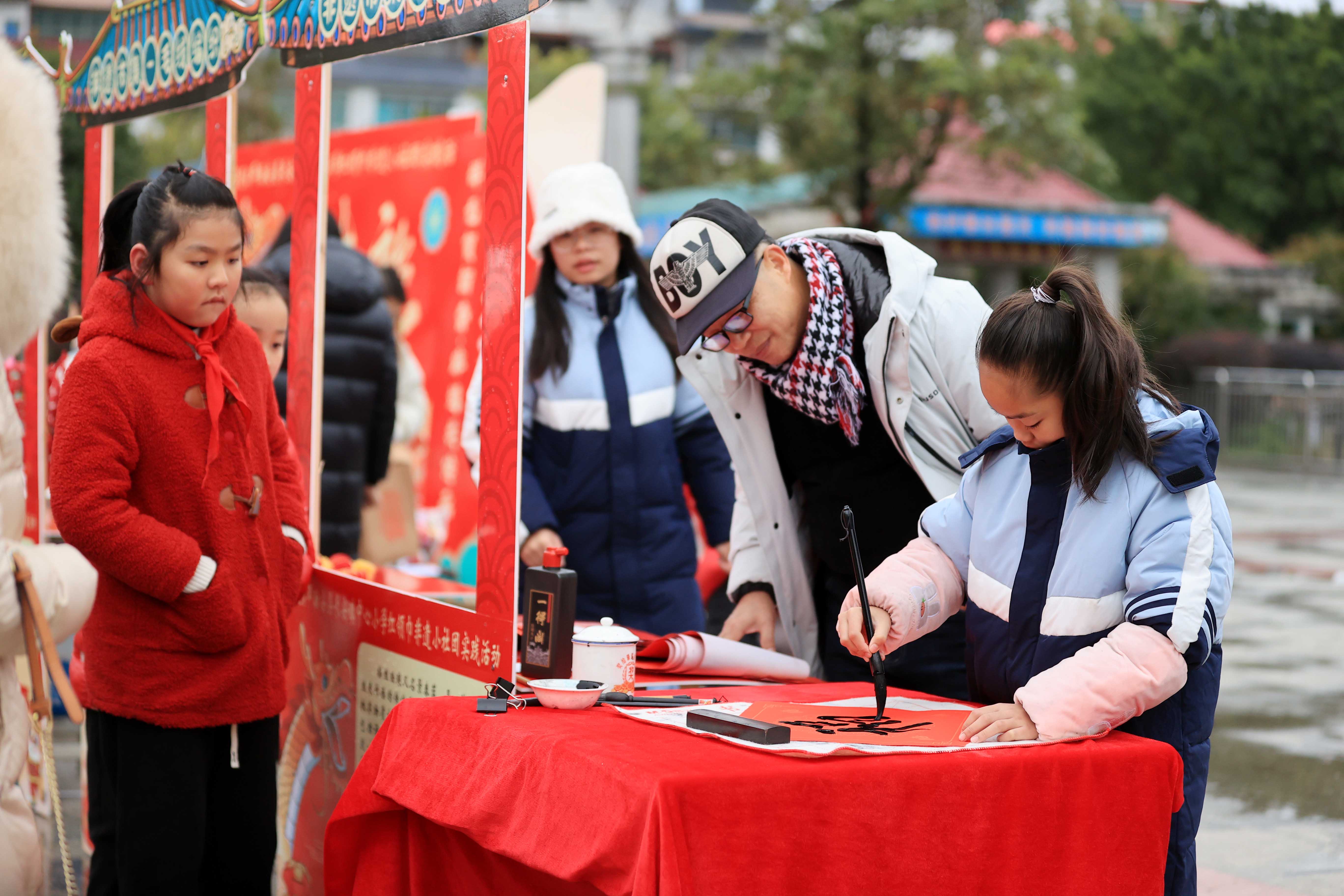 圖10：1月20日，在廣西柳州市融安縣長(zhǎng)安廣場(chǎng)，一名小學(xué)生在書寫福字，準(zhǔn)備贈(zèng)送市民。（譚凱興 攝）.JPG